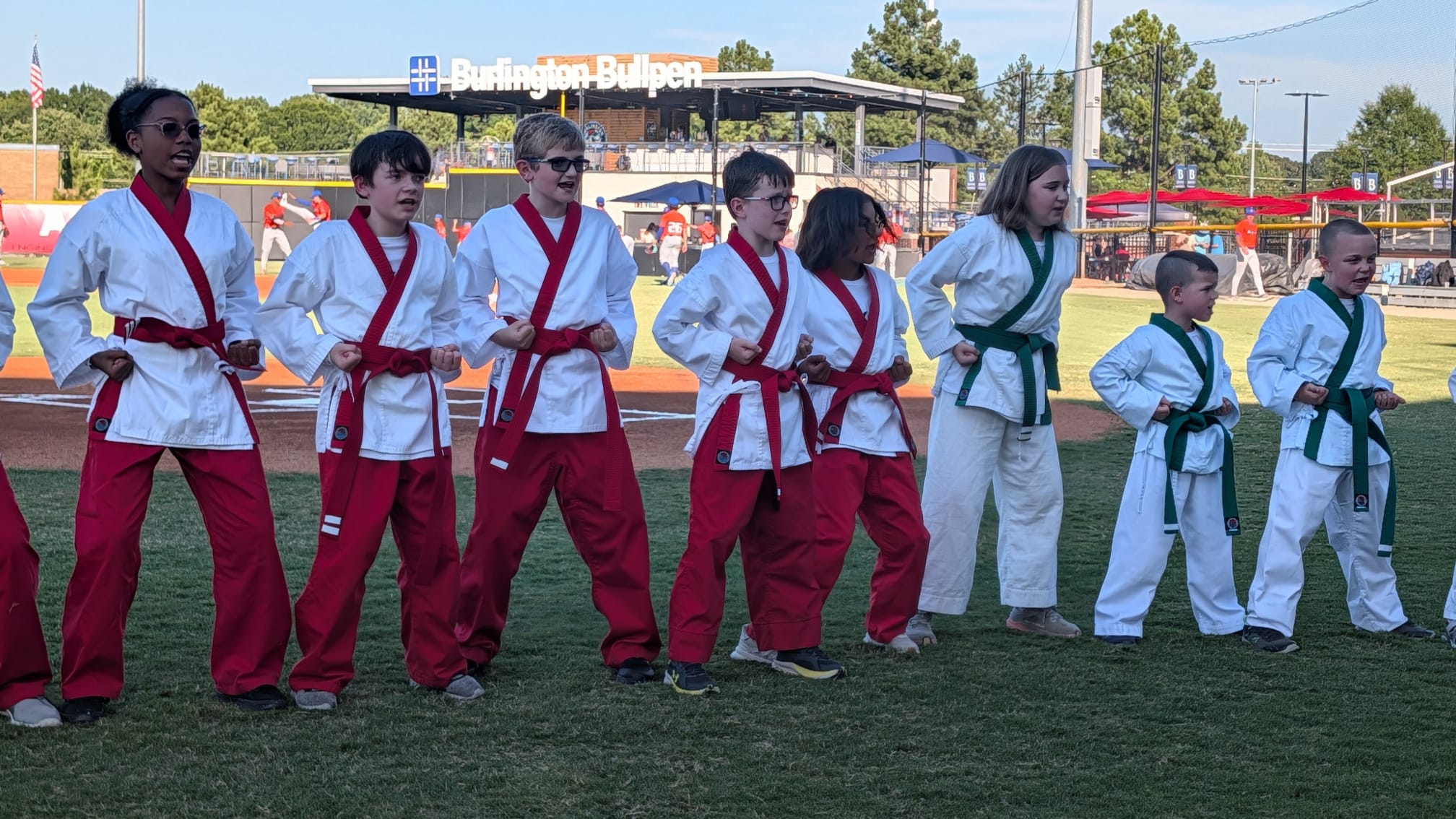 Red and green belt students lined up in stance in front of the Burlington Bullpen sign.